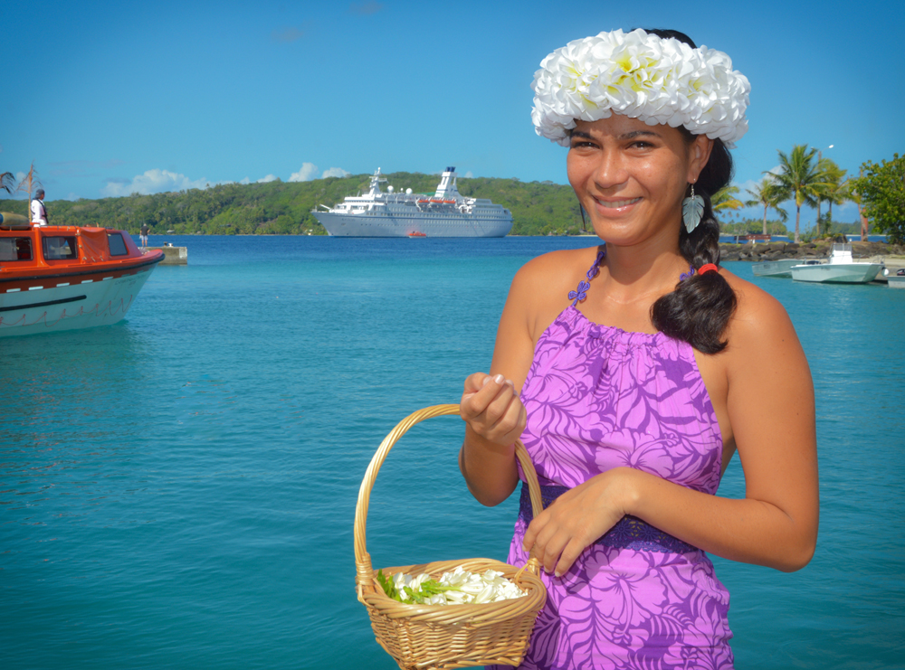 MS ASTOR vor Bora Bora mit junger Frau im Vordergrund.