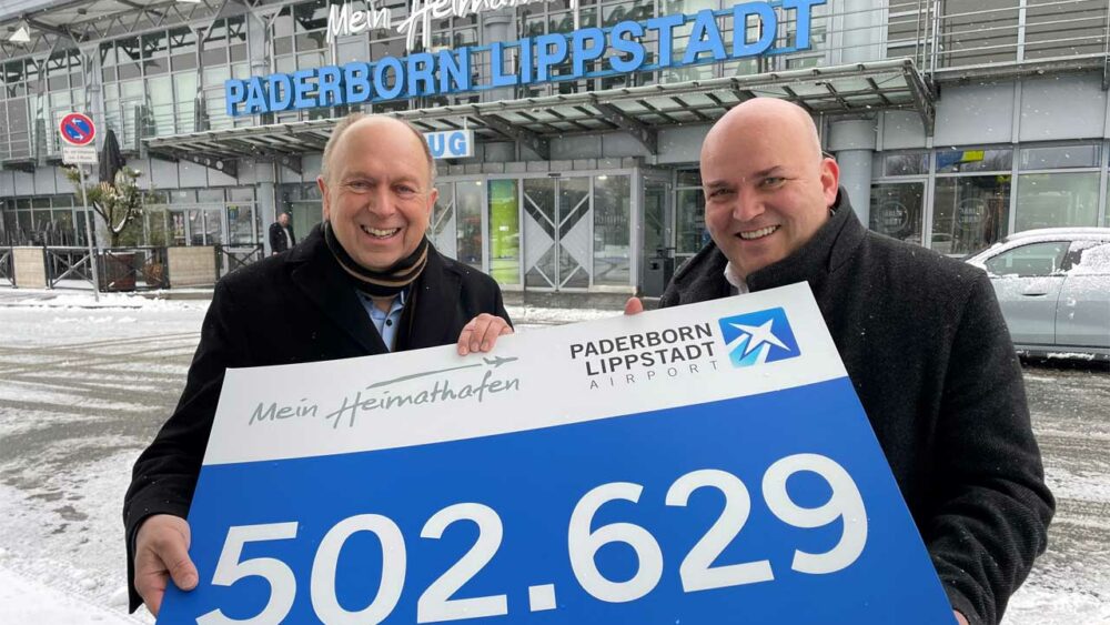 Aufsichtsratsvorsitzender Landrat Christoph Rüther und Geschäftsführer Roland Hüser halten Schild mit Zahl hoch.