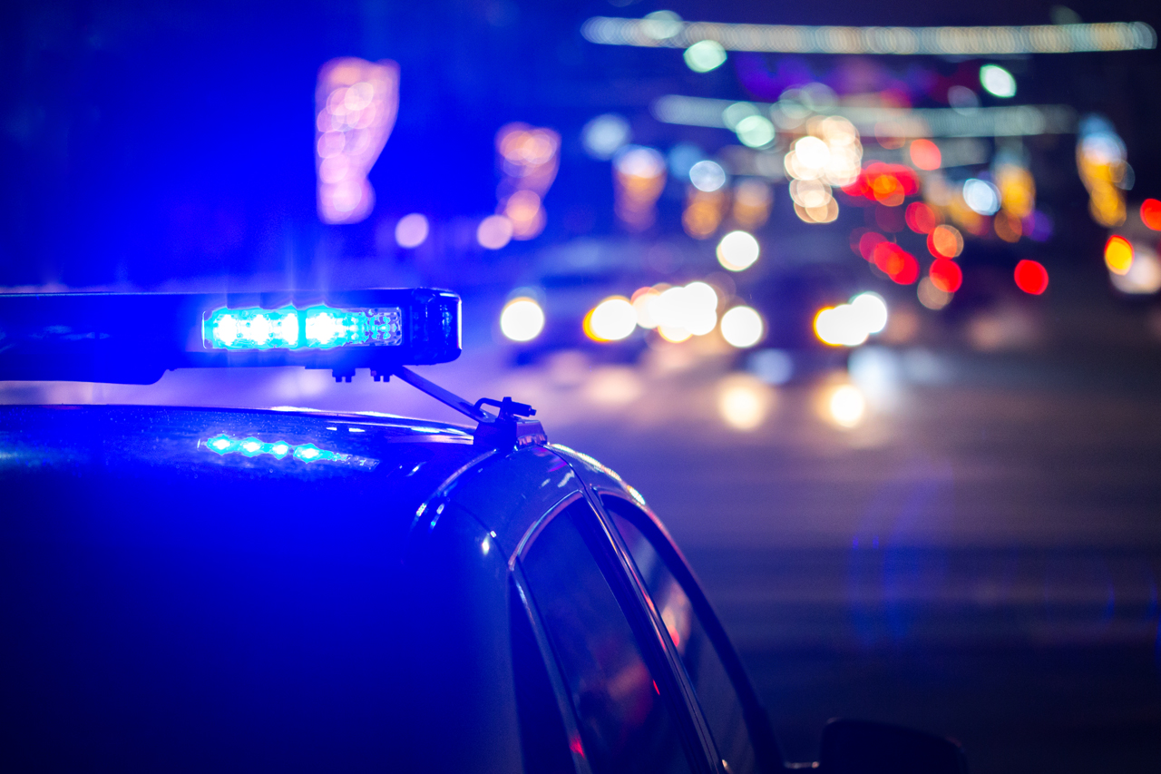 Polizeiauto bei Nacht mit Lichtern der Stadt im Hintergrund